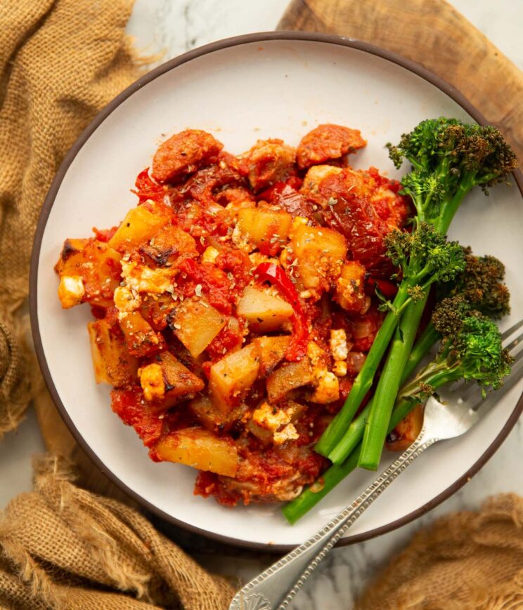 overhead shot of chicken chorizo potato bake on small white plate with broccolini