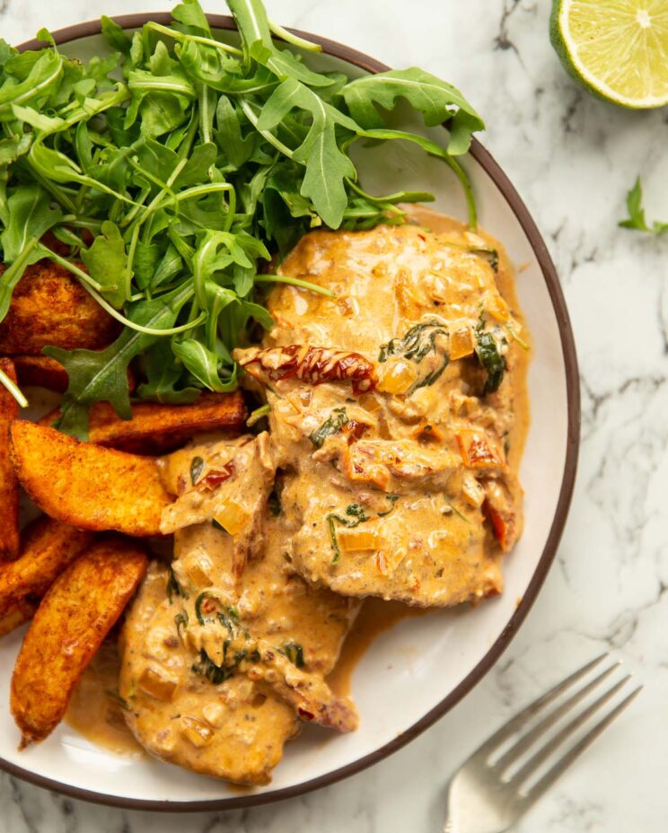 overhead shot of cajun chicken on small white plate with wedges and rocket