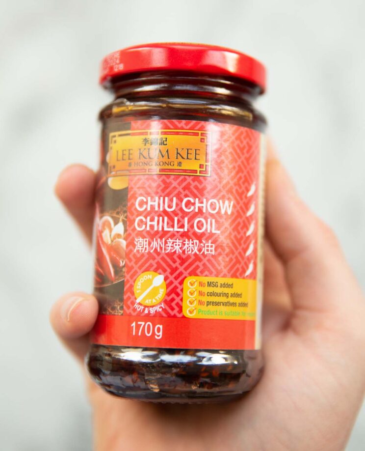 close up overhead shot of hand holding jar of chilli oil