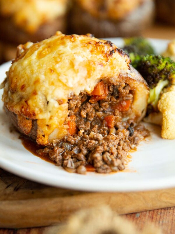 cottage pie loaded potato sliced in half on small white plate with roasted broccoli and cauliflower