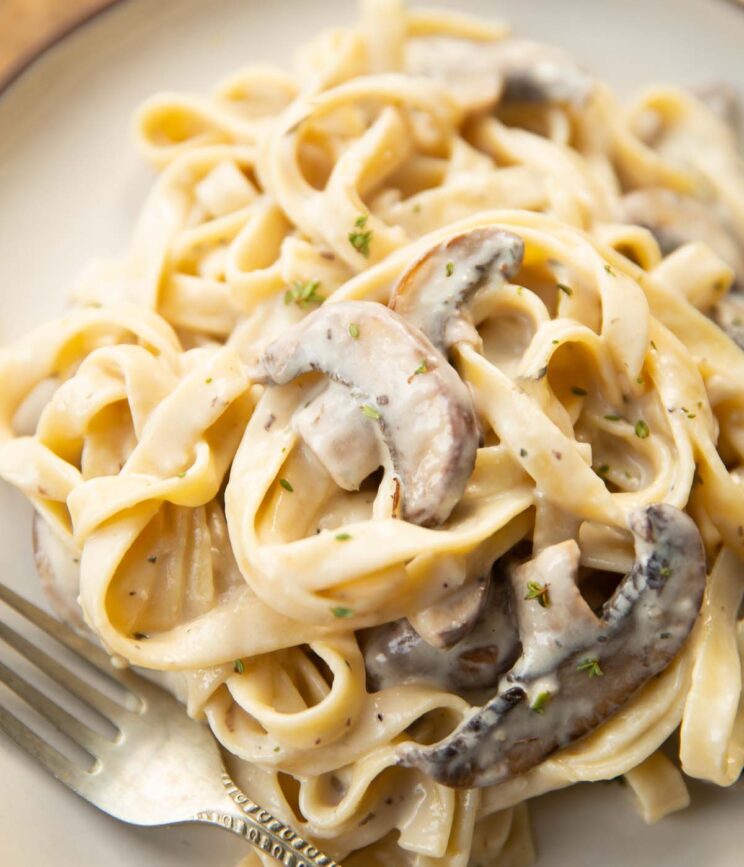 close up shot of creamy mushroom tagliatelle on small white plate with silver fork