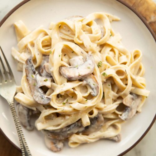 overhead shot of mushroom tagliatelle on small white plate with silver fork