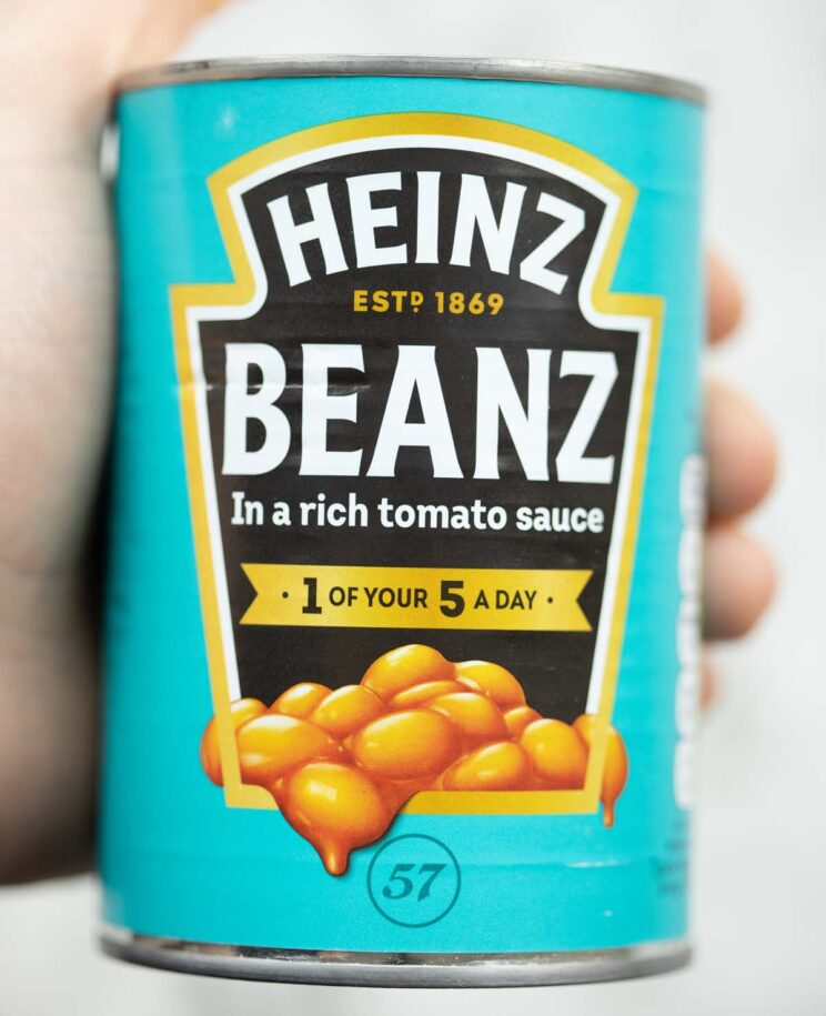 close up shot of hand holding tin of baked beans