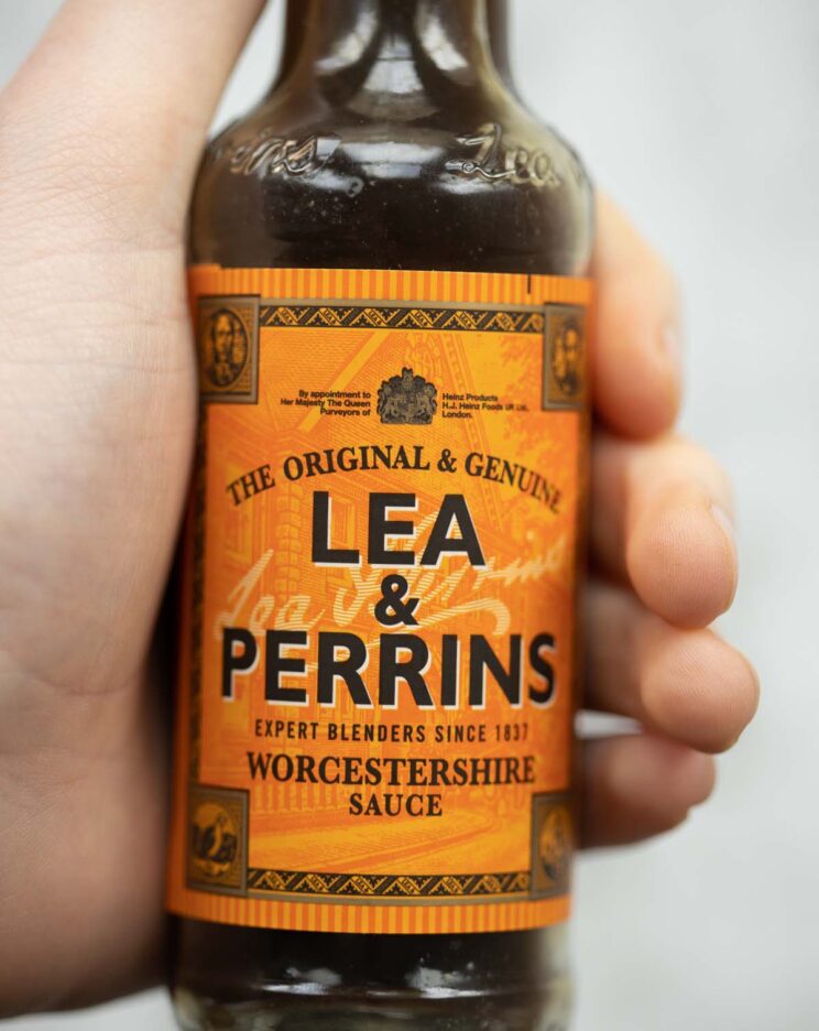 close up shot of hand holding bottle of Worcestershire sauce