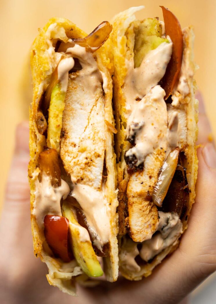 overhead close up shot of hand holding halved chipotle chicken quesadilla showing filling