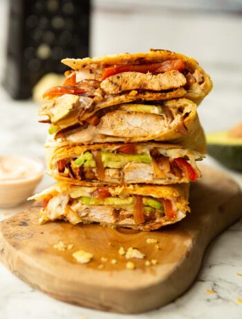 4 chipotle chicken quesadillas quarters stacked on each other on wooden board