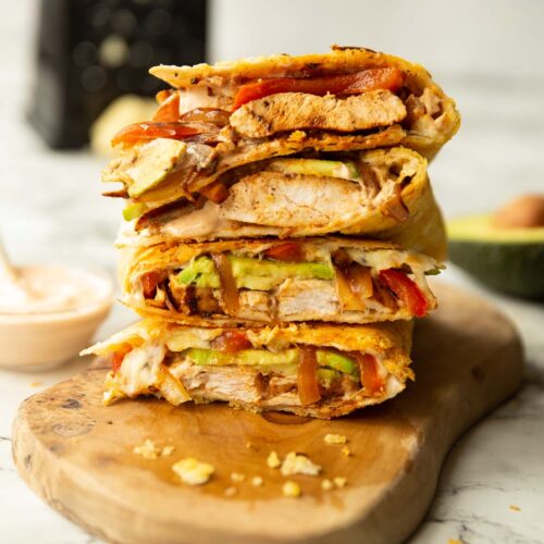 4 chipotle chicken quesadillas quarters stacked on each other on wooden board