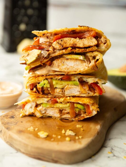 4 chipotle chicken quesadillas quarters stacked on each other on wooden board