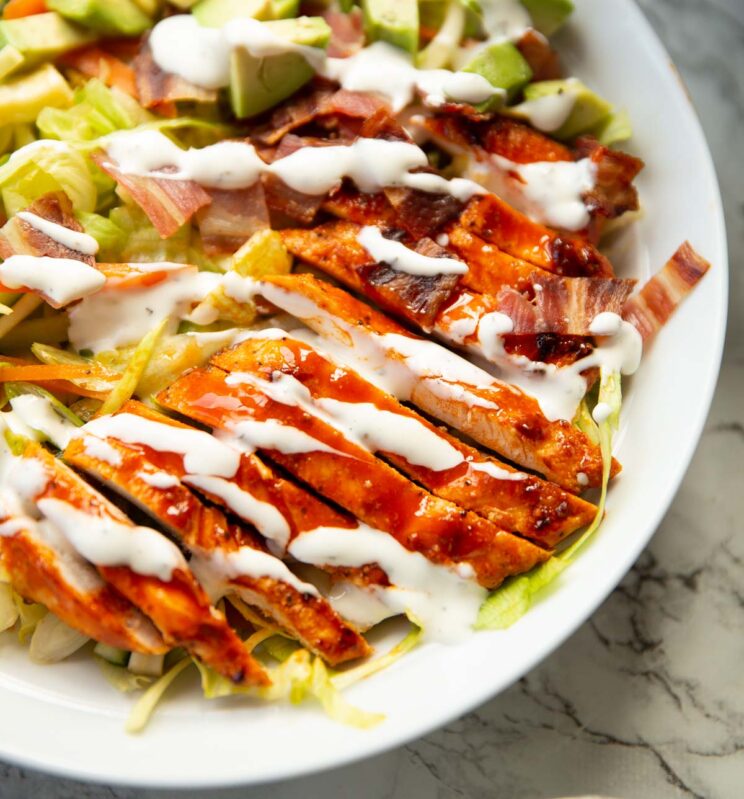 close up shot of buffalo chicken salad in large white dish on marble background