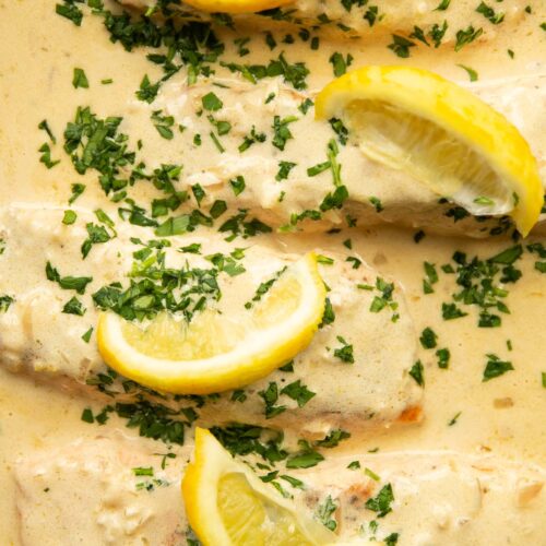 overhead shot of 4 salmon fillet sin lemon cream sauce in pan