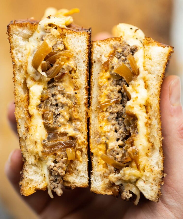 close up overhead shot of hands holding patty melt sliced open