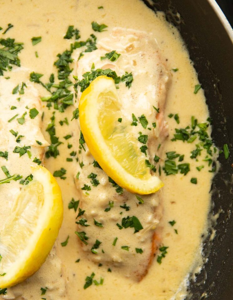 overhead shot of salmon fillet in creamy lemon sauce in pan