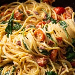 close up shot of blt pasta in pan with tongs twirling pasta