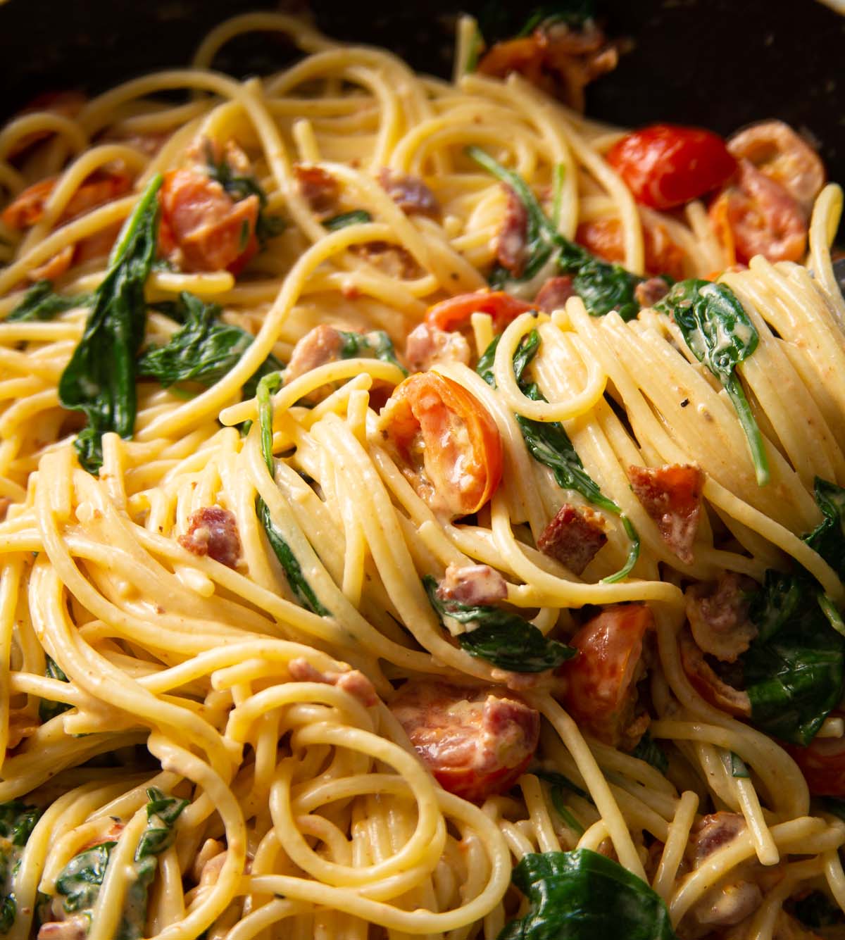 close up shot of blt pasta in pan with tongs twirling pasta