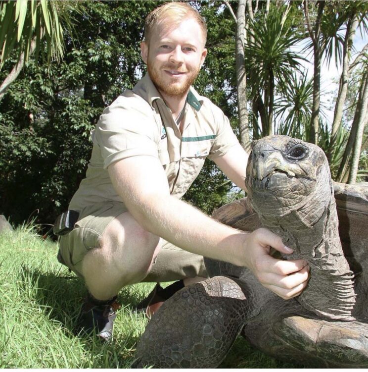 photo of chris collins holding giant tortoise at Melbourne zoo
