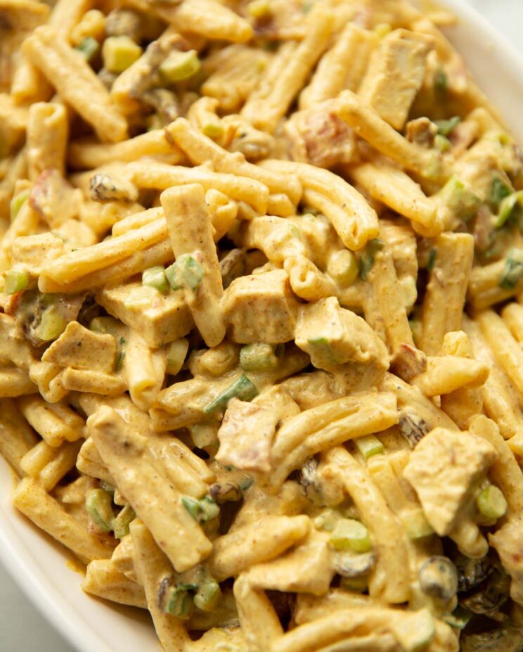 close up shot of coronation chicken pasta salad in large white dish