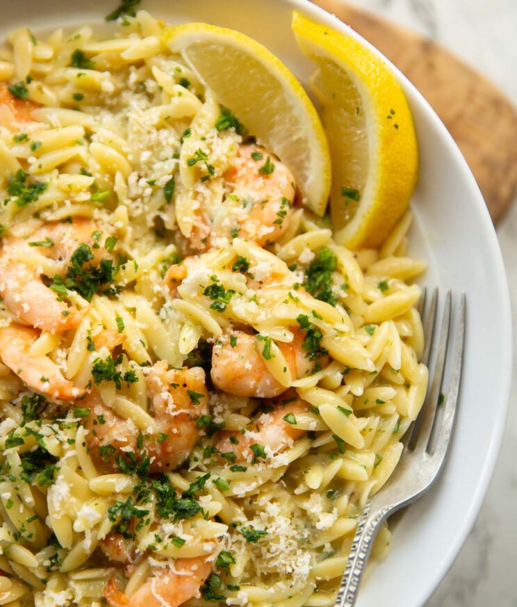 close up shot of garlic butter orzo in large white plate with silver fork