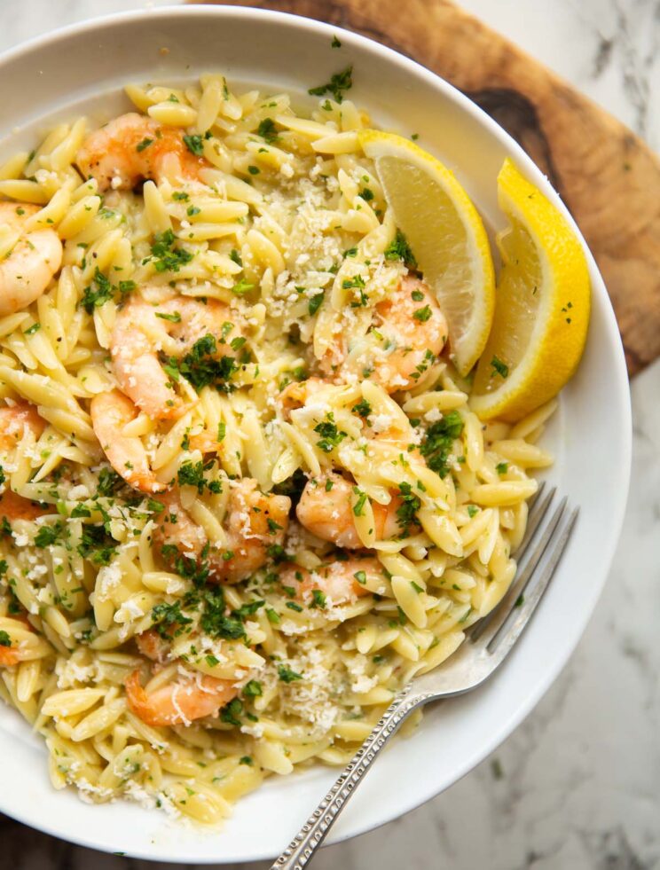 close up over head shot of garlic butter prawn orzo in large white bowl with silver fork