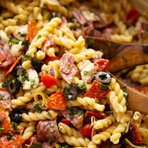 close up shot of Italian sub pasta salad in salad bowl with wooden salad tossers