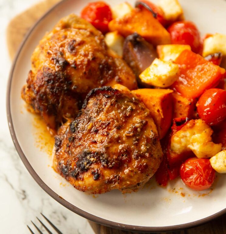 Nando's peri peri chicken traybake on small white plate on wooden board