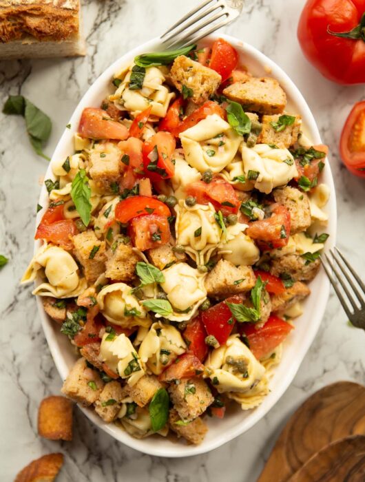 overhead shot of Panzanella tortellini salad in large white dish on marble background