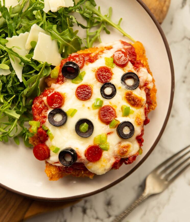 overhead shot of pizza parmesan on small white plate with rocket salad