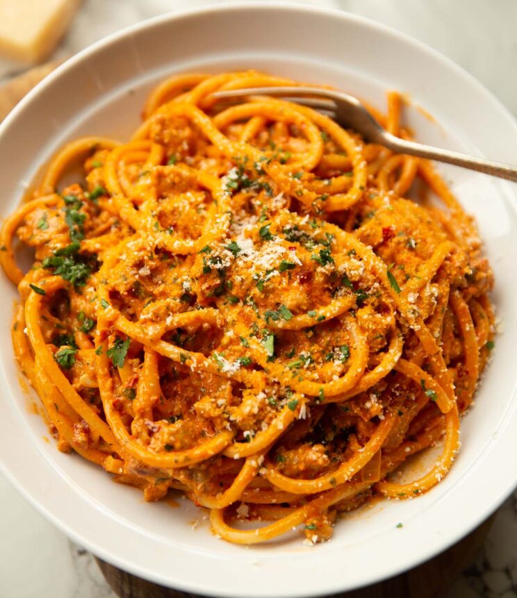 close up shot of harissa pasta with sausage in large white bowl