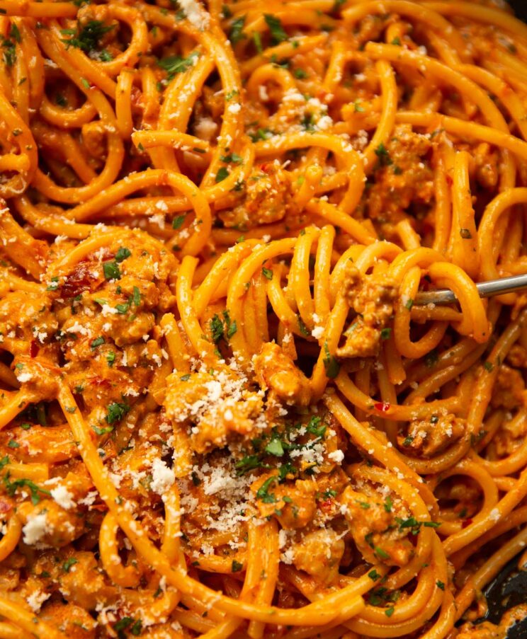 close up shot of harissa sausage pasta in pan garnished with parmesan and parsley