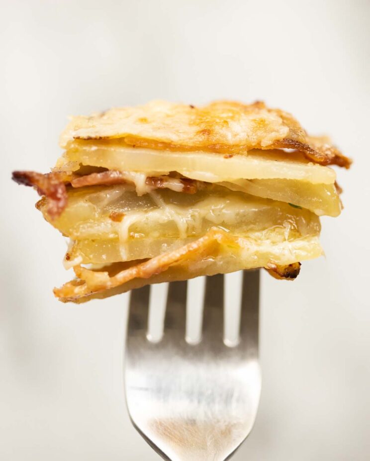 close up shot of half a cheese and bacon potato stacks on silver fork