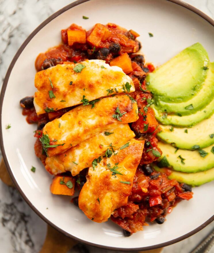 close up overhead shot of halloumi bake served with avocado on small white plate