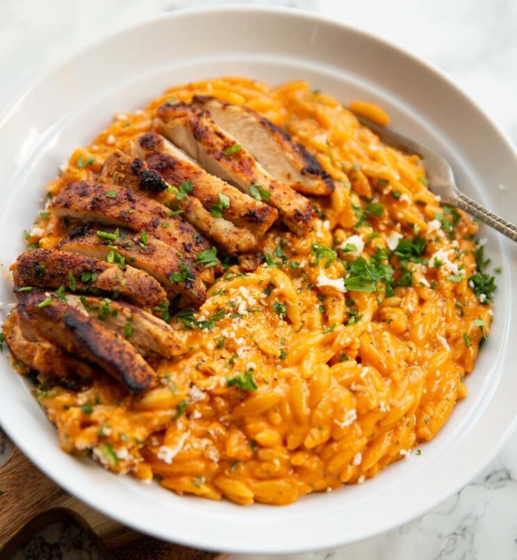'nduja orzo with grilled chicken in large white bowl with silver fork