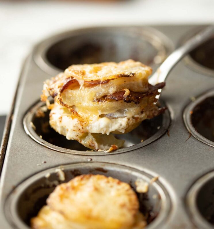 close up shot of spoon lifting potato stack out of muffin tin
