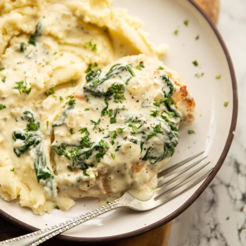 Spinach Boursin Chicken on small white plate with mashed potato and silver fork