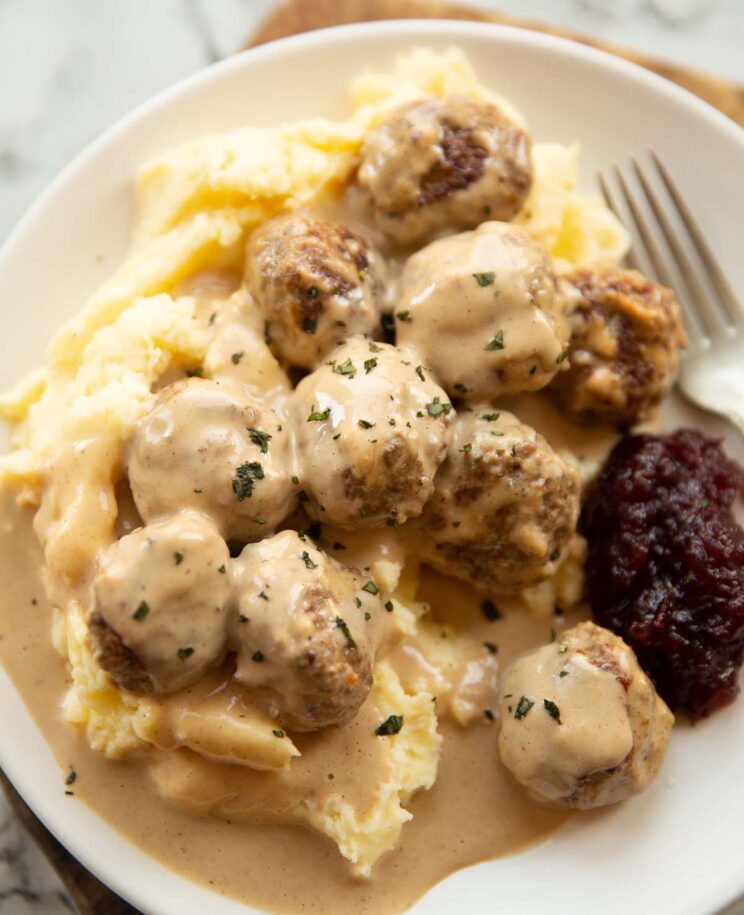 close up shot of Swedish meatballs on mashed potato on small white plate