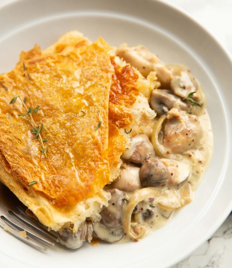 chicken mushroom puff pastry pie in large white bowl with silver fork