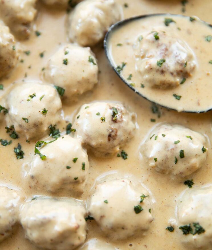 close up shot of Swedish meatballs in pan with serving spoon digging in