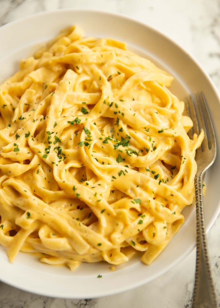 close up shot of pumpkin alfredo in large white bowl with silver fork