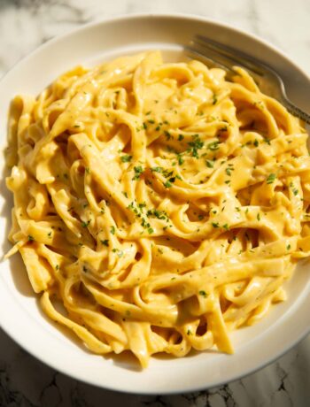 roasted pumpkin alfredo in large white bowl garnished with parsley