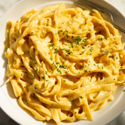 roasted pumpkin alfredo in large white bowl garnished with parsley