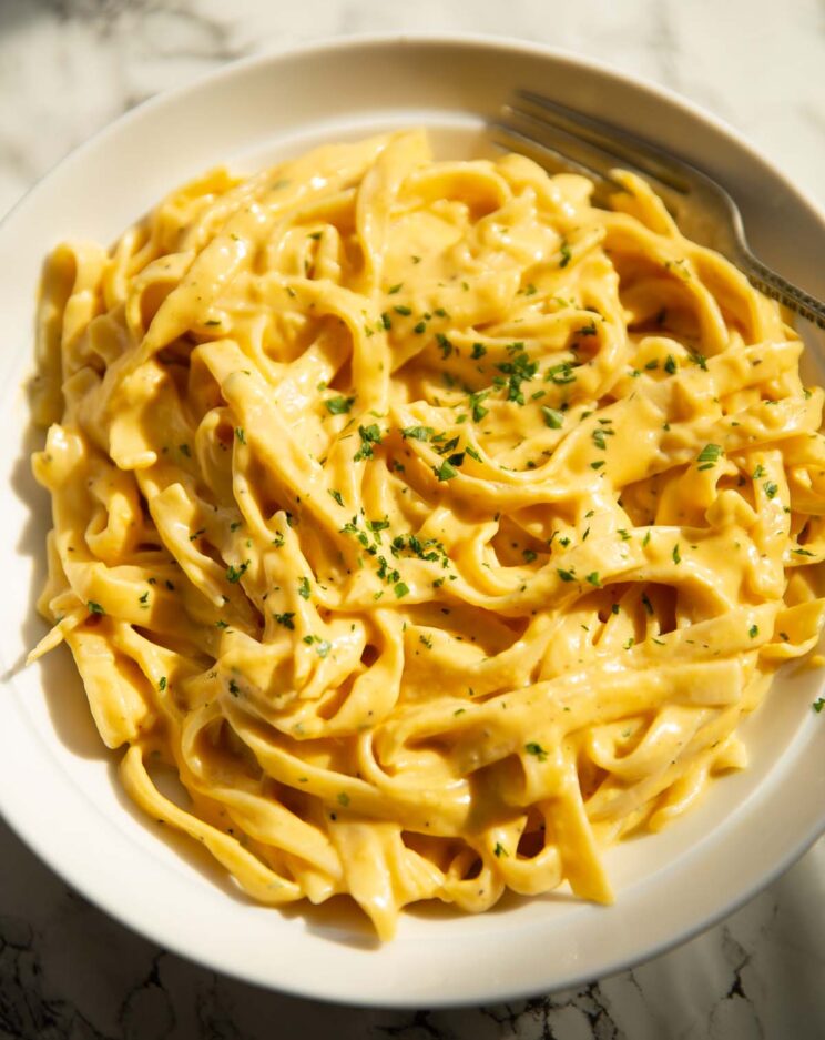 roasted pumpkin alfredo in large white bowl garnished with parsley