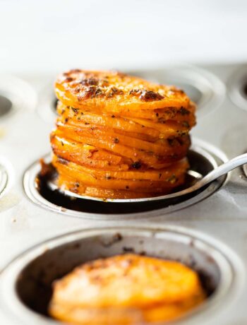 close up shot of silver spoon scooping sweet potato stacks out of muffin tin