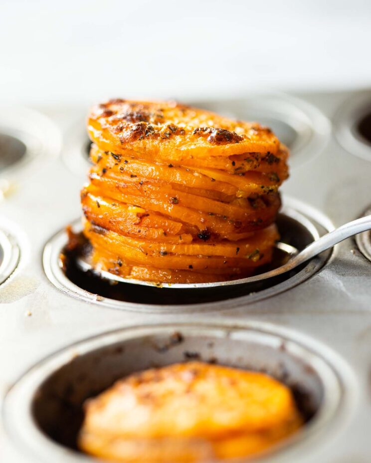 close up shot of silver spoon scooping sweet potato stacks out of muffin tin
