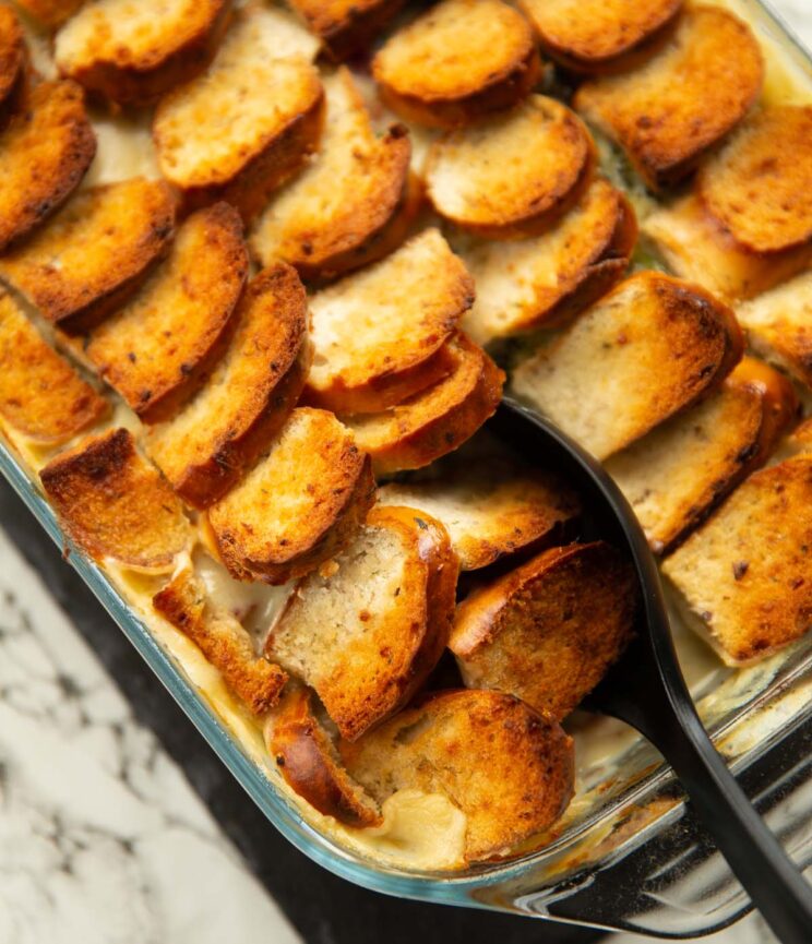 close up shot of black serving spoon digging in to chicken broccoli bagel bake