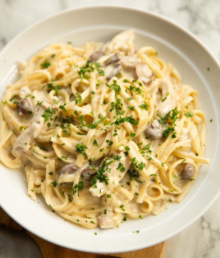 chicken tetrazzini served in a large white dish garnished with fresh parsley