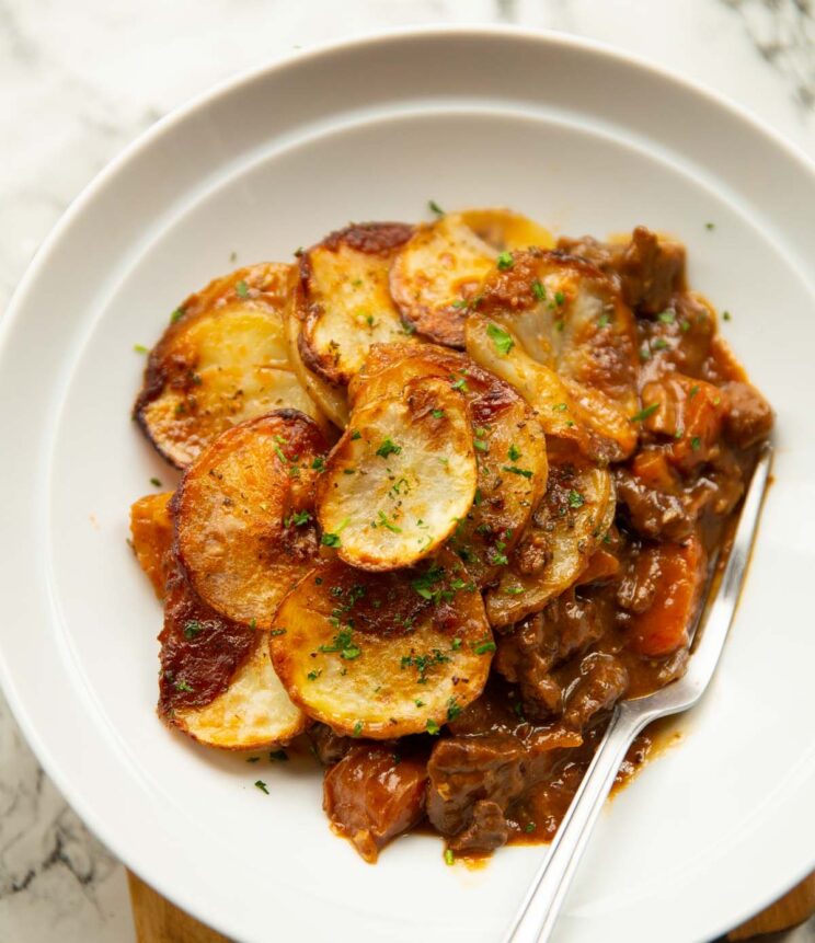 steak and potatoes pie served in a large white dish with silver fork