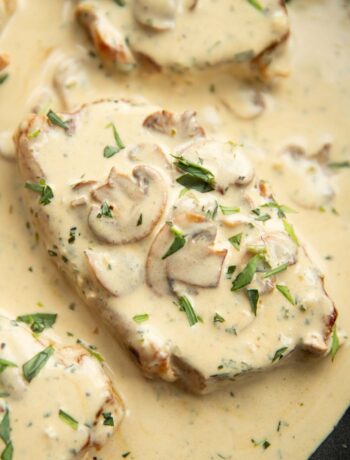 close up overhead shot of pork chop in pan with mushroom sauce