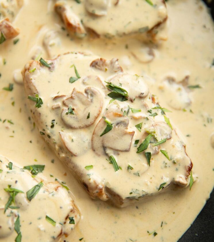 close up overhead shot of pork chop in pan with mushroom sauce