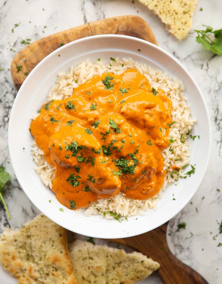 overhead shot of butter chicken served on rice in large white bowl