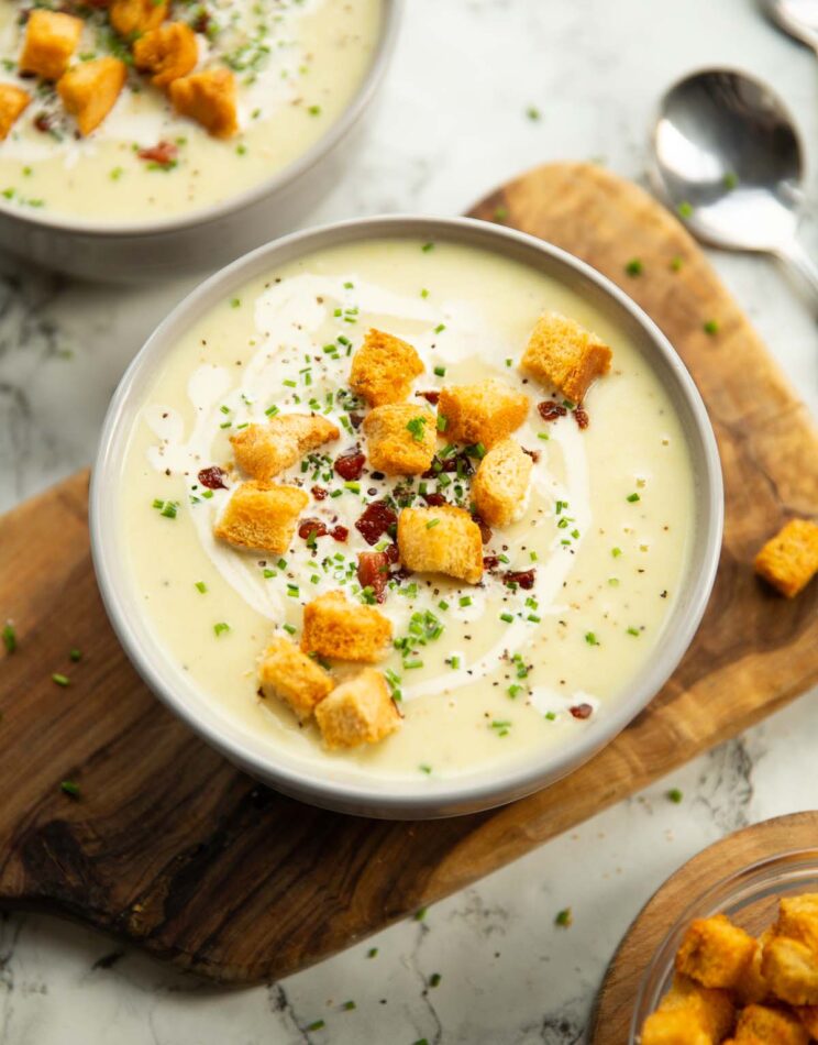 leek potato soup served in small white bowl on wooden chopping board