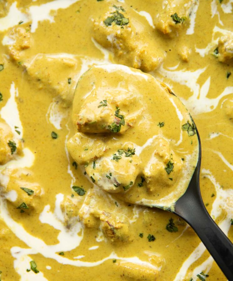 close up overhead shot of spoon digging into pan of chicken korma